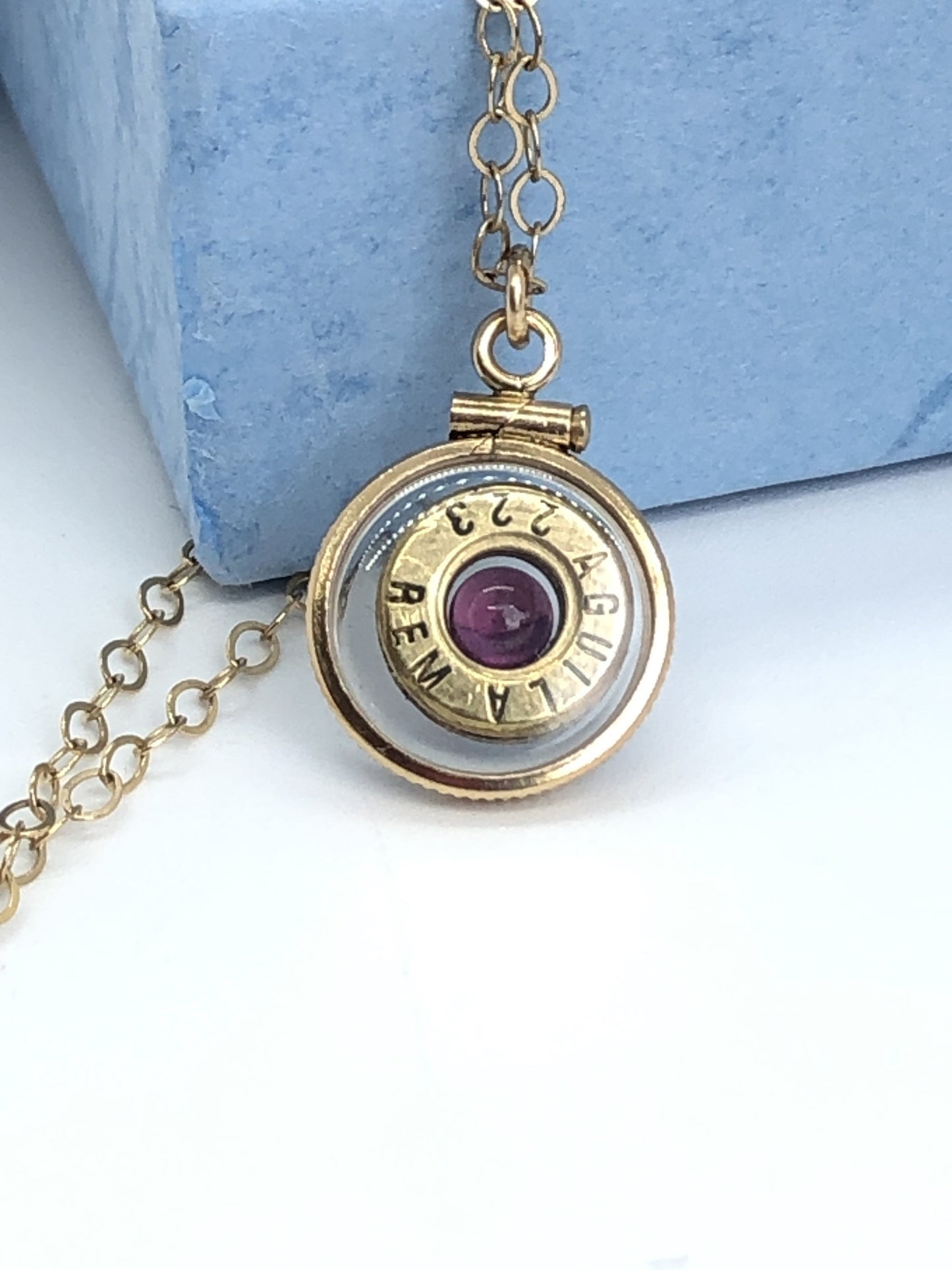 Handmade 14k gold filled .223 cal bullet view locket, finished with a 4mm genuine garnet gemstone, view from both sides