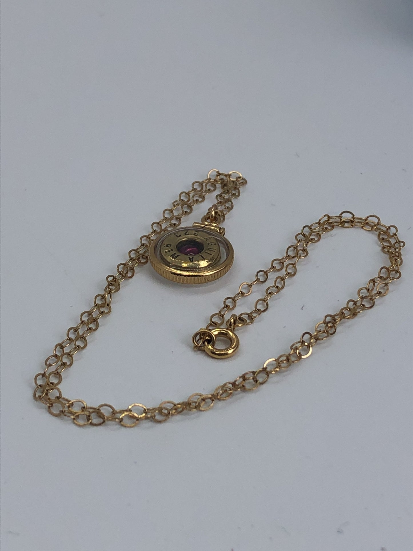 Handmade 14k gold filled .223 cal bullet view locket, finished with a 4mm genuine garnet gemstone, view from both sides
